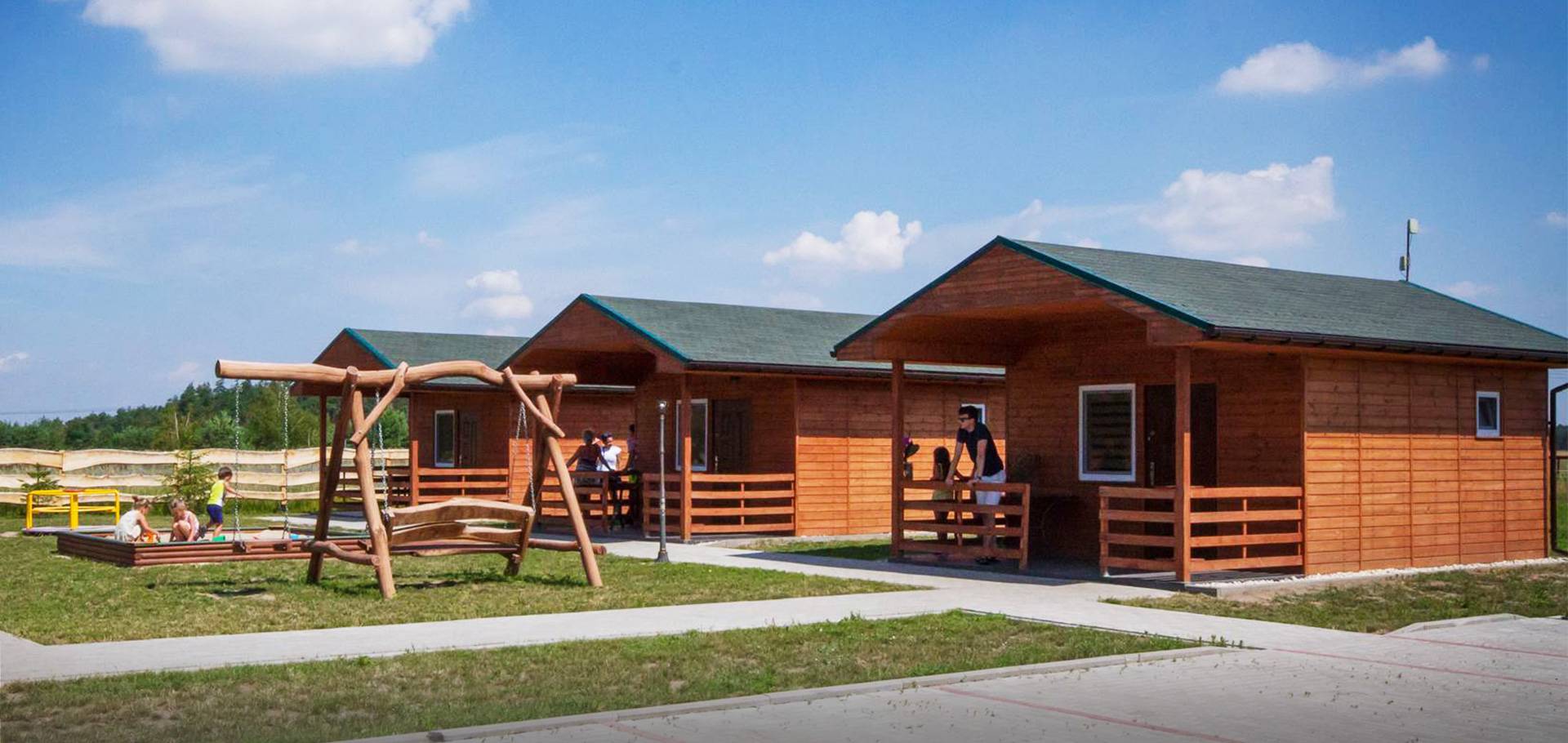 Slajd #2 - ludzie przy domkach letniskowych